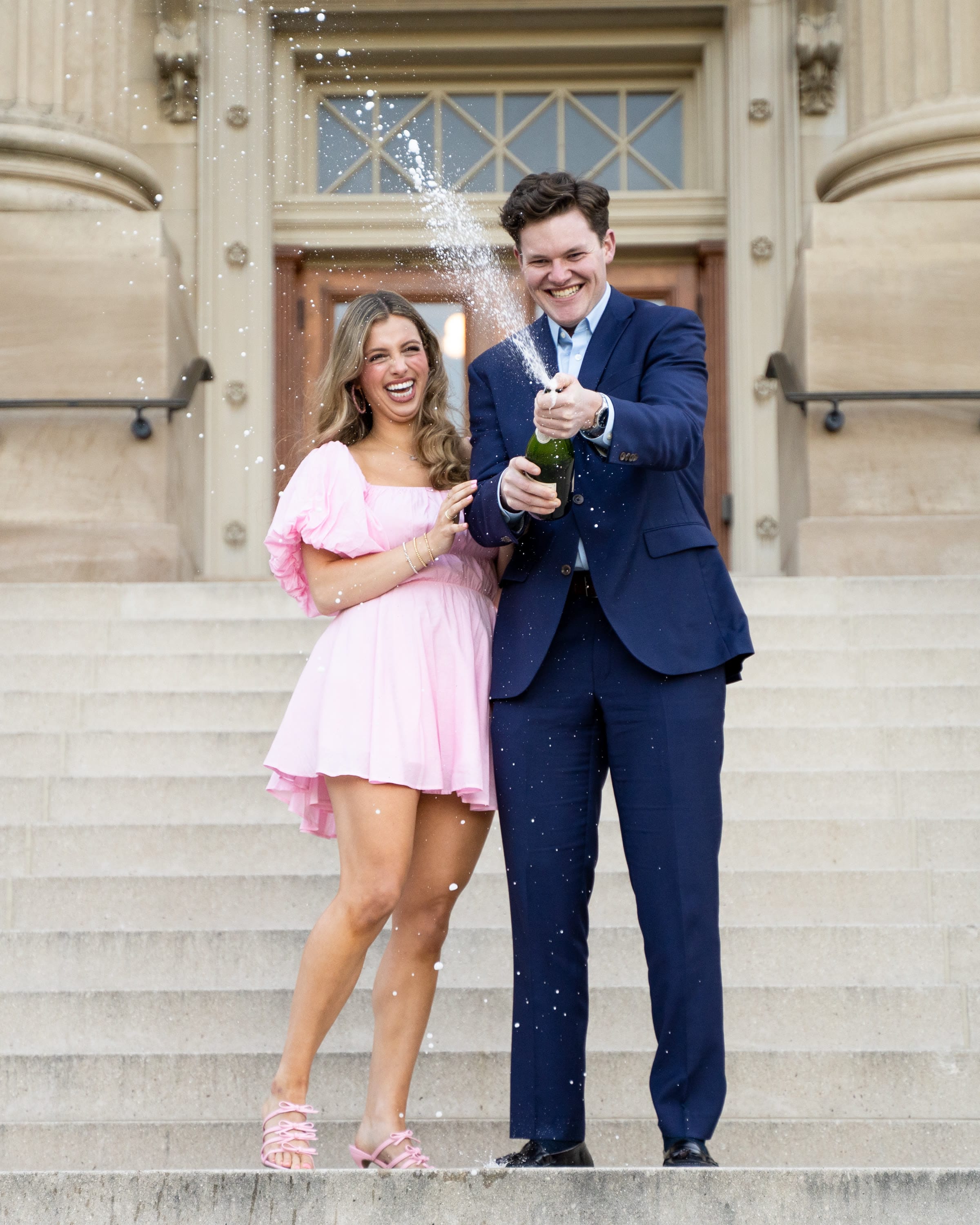 Newly engaged couple celebrating with champagne on a staircase
