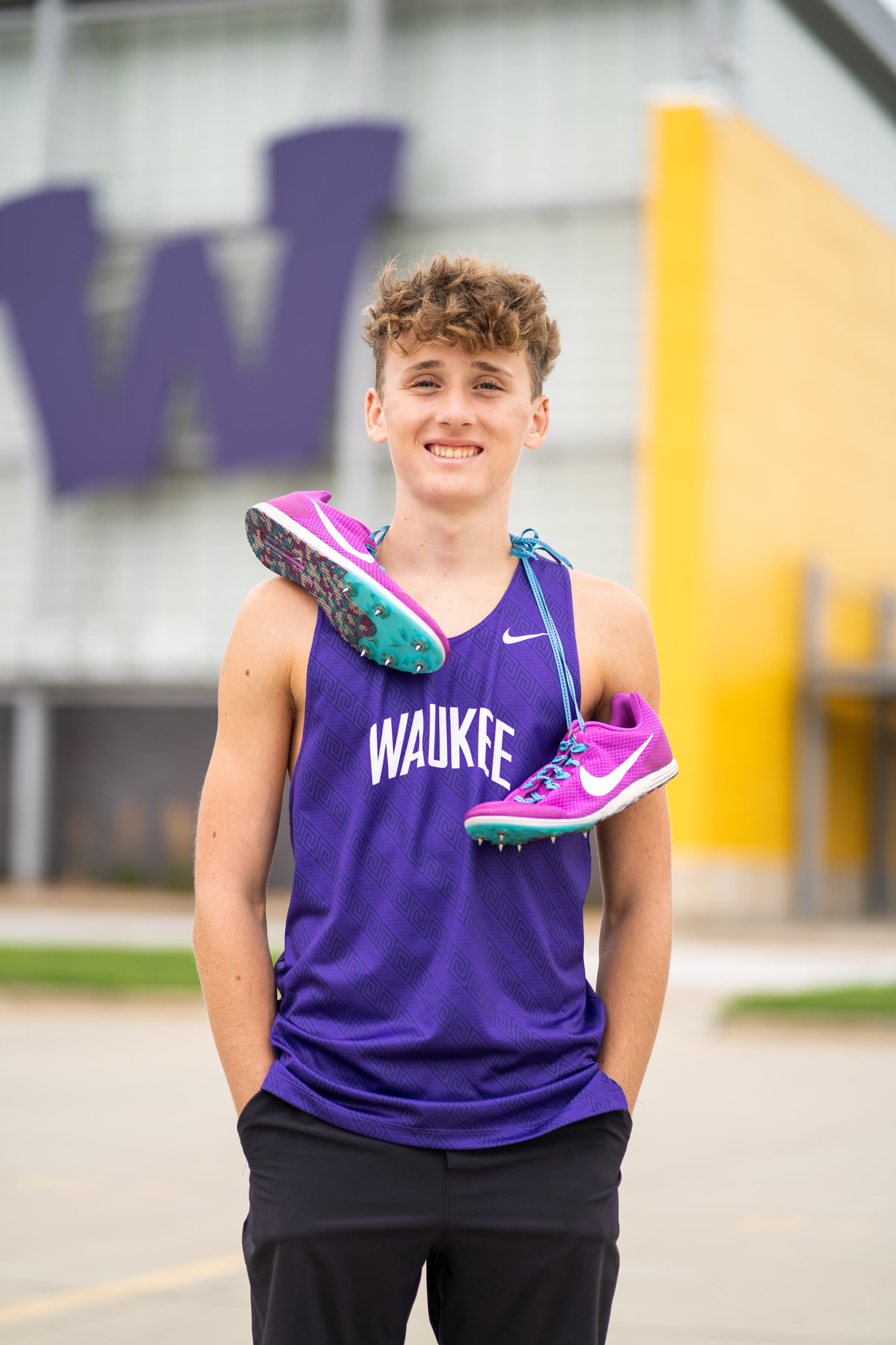 Senior track athlete portrait holding spikes over his shoulder