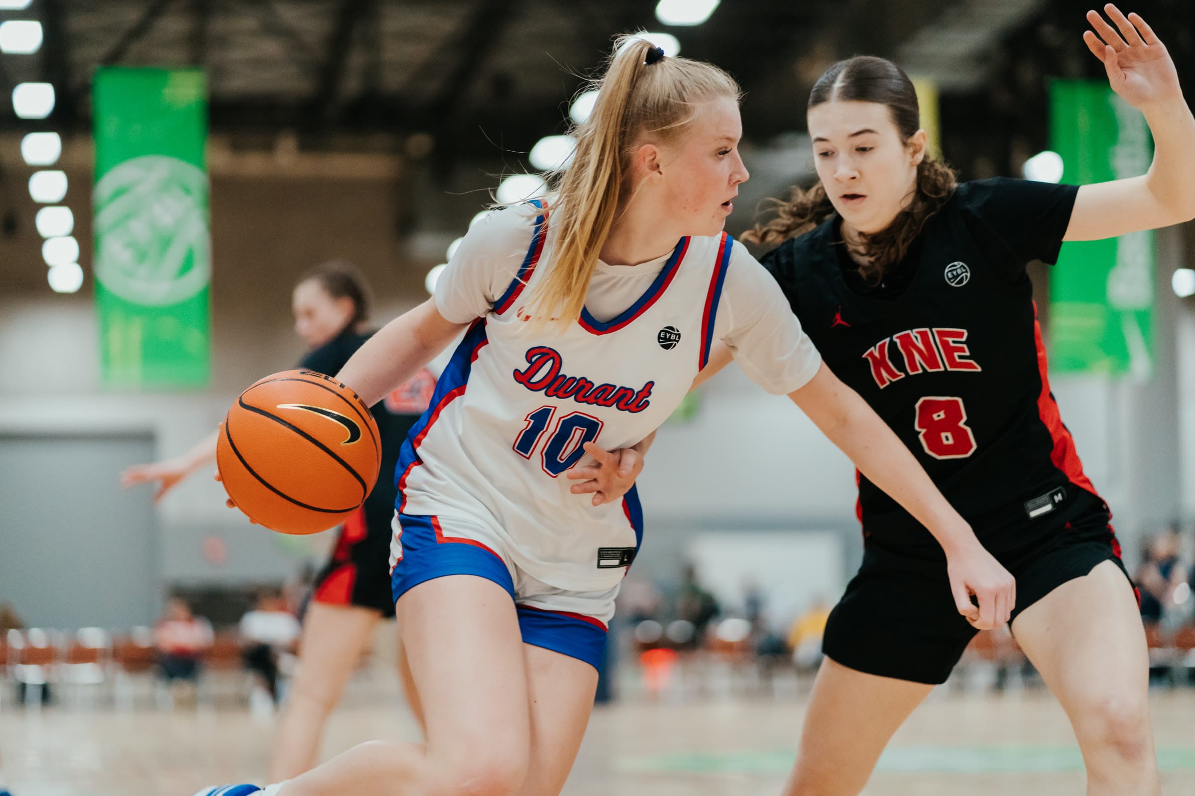 Basketball player driving past a defender at an EYBL tournament